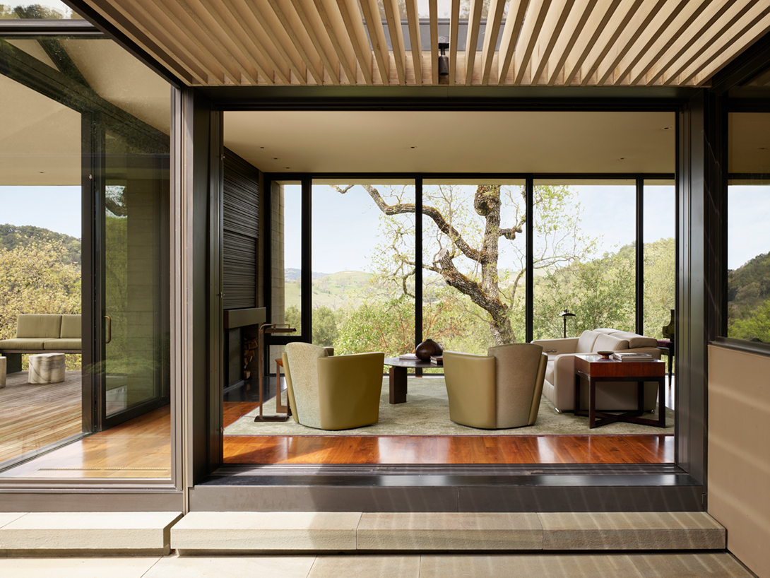 A large oak tree provides shade as well as a sculptural element outside this nature inspired living room;