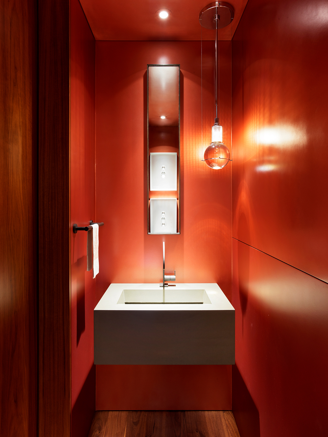 powder room walls are covered in an automotive paint in a deep-orange hue