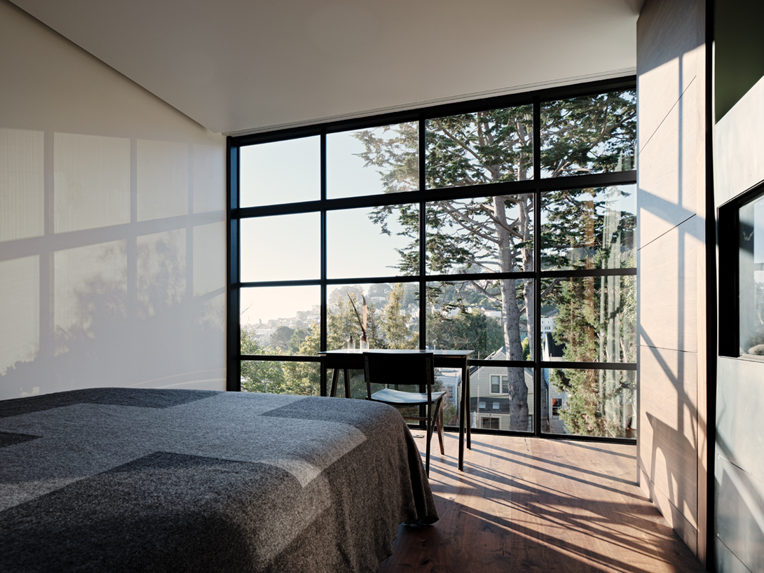 Sunlight pours in through a glass- and-steel wall in the master bedroom 