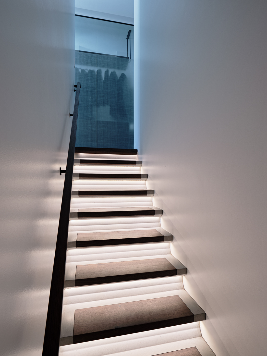 An illuminated concrete- and-walnut staircase links the second floor and the ground level.