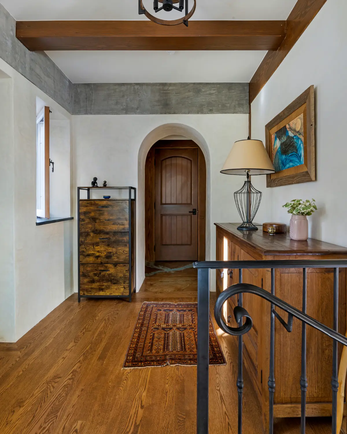 Hallway inside the ADU with wood floors, arched doorway, rustic furnishings, and decorative ceiling beams, capturing old-world charm.