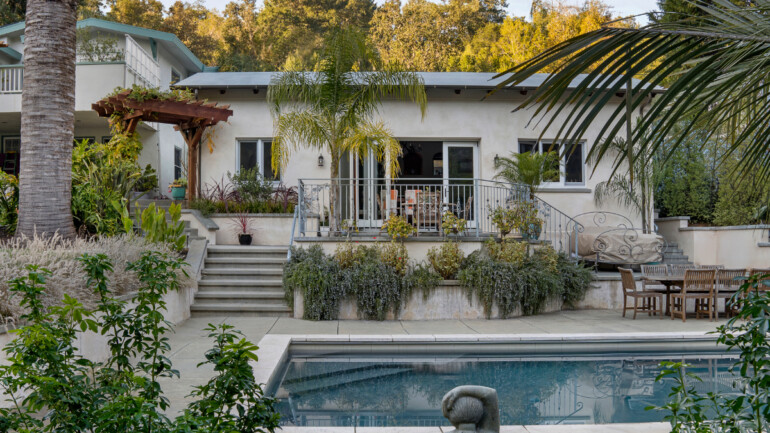 Exterior of the Calders’ ADU in Fairfax, with stairs leading to the patio, surrounded by greenery and overlooking a backyard swimming pool.