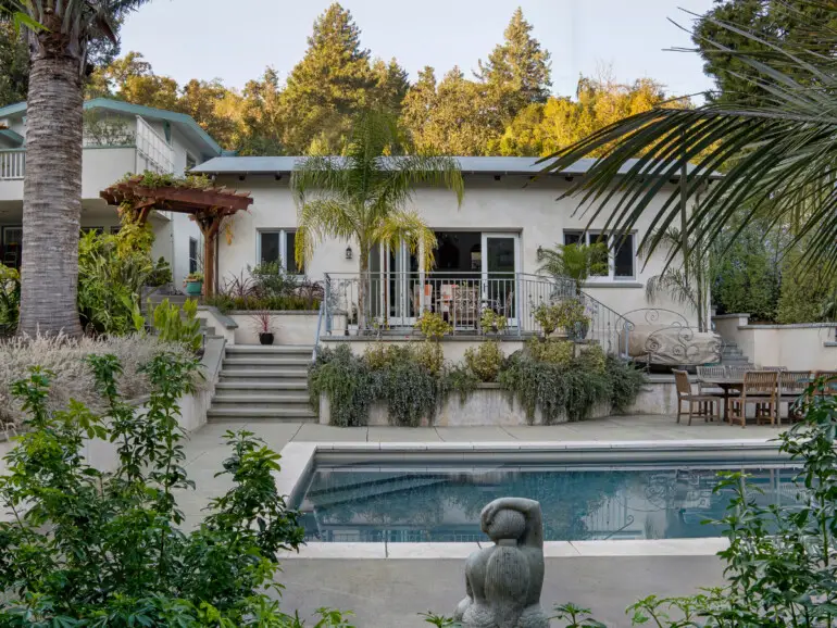 Exterior of the Calders’ ADU in Fairfax, with stairs leading to the patio, surrounded by greenery and overlooking a backyard swimming pool.
