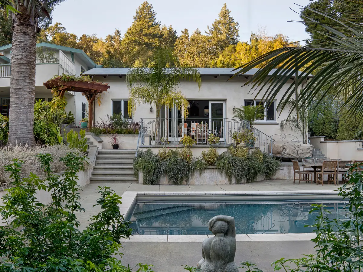 Exterior of the Calders’ ADU in Fairfax, with stairs leading to the patio, surrounded by greenery and overlooking a backyard swimming pool.