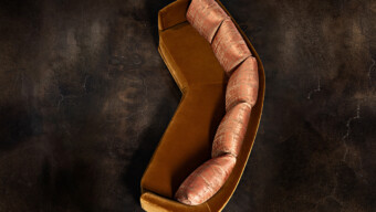 A modern curved couch complemented by brown pillows, offering comfort and elegance in the living space.