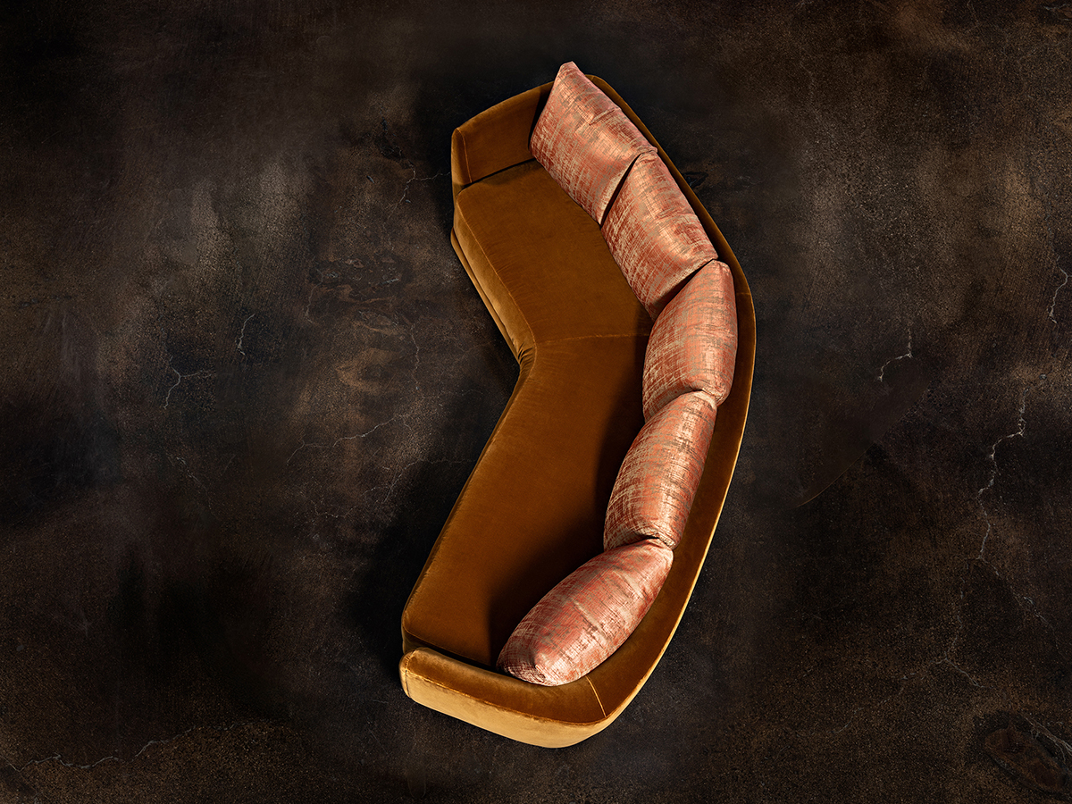 A modern curved couch complemented by brown pillows, offering comfort and elegance in the living space.