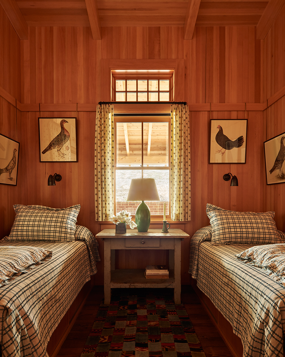A cozy bedroom featuring two beds and a small table in the center, designed for comfort and relaxation.