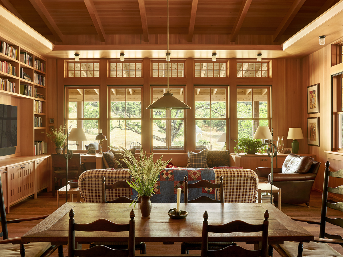  A cozy living room featuring a wooden table surrounded by four chairs, with soft lighting and decorative elements.