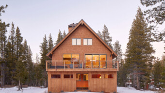 A cozy cabin surrounded by snow, featuring a spacious deck for outdoor relaxation.