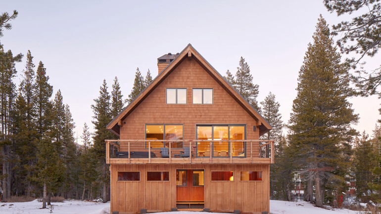 A cozy cabin surrounded by snow, featuring a spacious deck for outdoor relaxation.