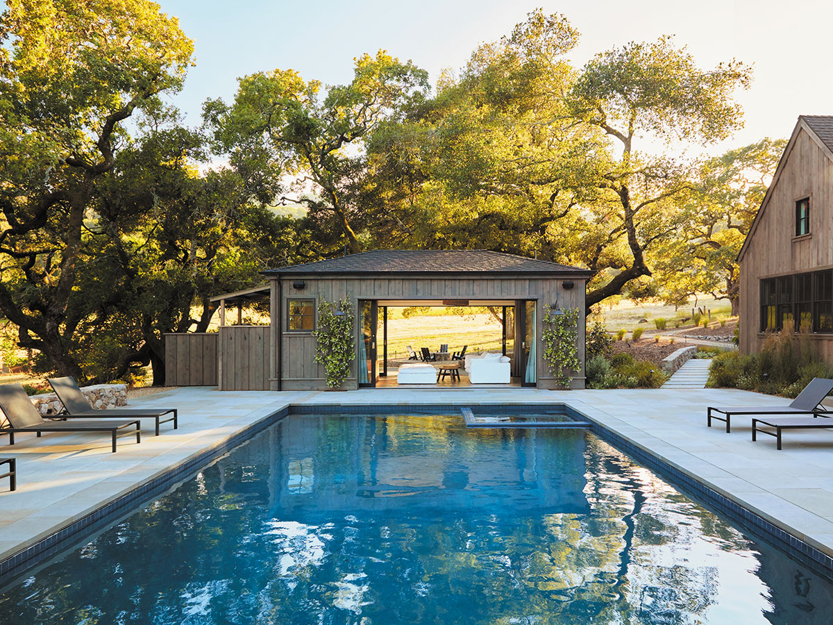 A pool with lounge chairs is situated in front of a house, creating a relaxing outdoor space.