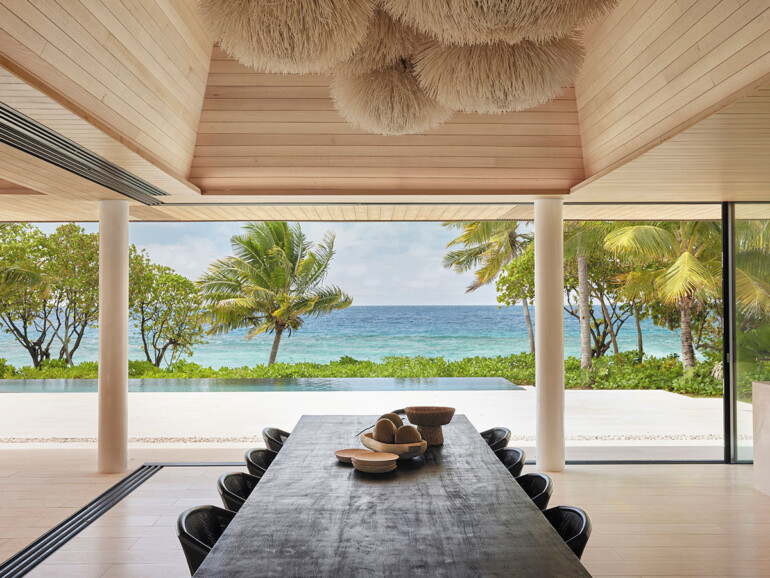 A dining table with chairs, featuring a stunning view of the ocean, creating a tranquil dining atmosphere.