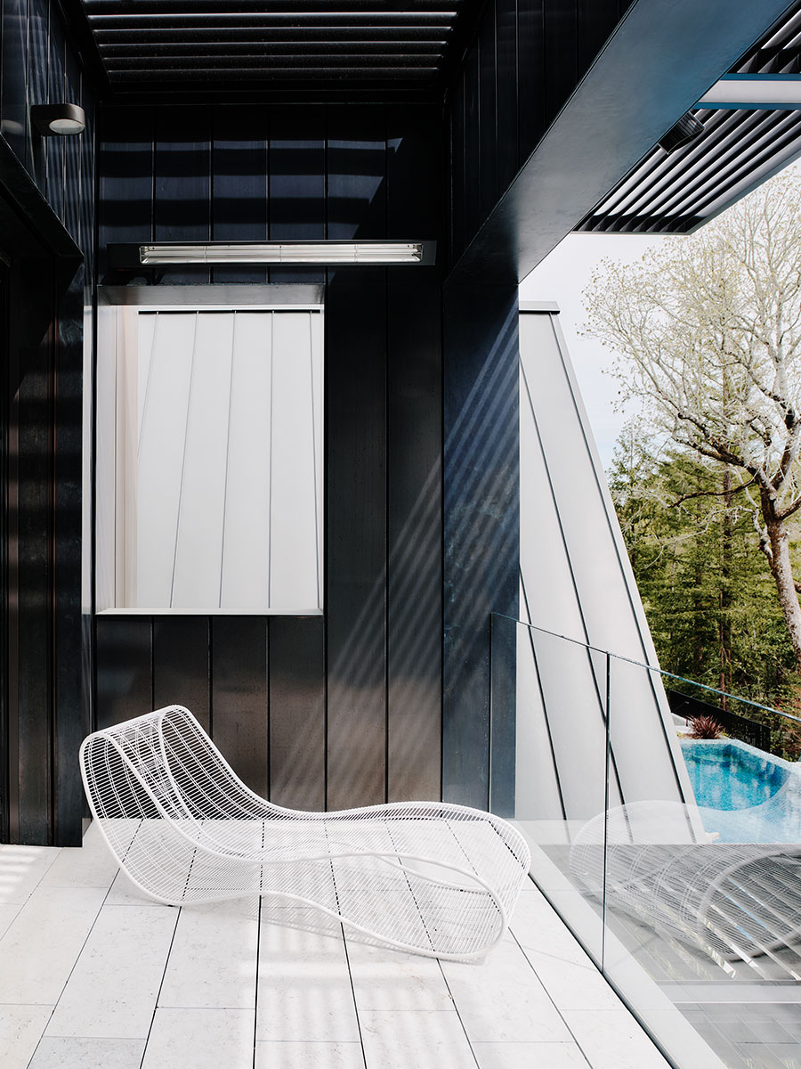 A modern patio featuring a white chair beside a sparkling pool under clear blue skies.