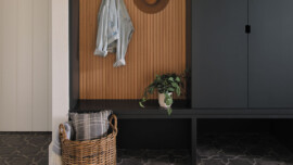 A monochrome entryway with a wooden bench against the wall and a basket placed nearby.