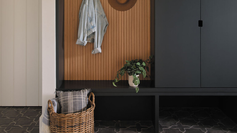 A monochrome entryway with a wooden bench against the wall and a basket placed nearby.