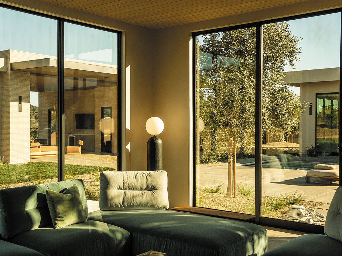 A bright living room featuring large windows and a comfortable couch, creating an inviting atmosphere.