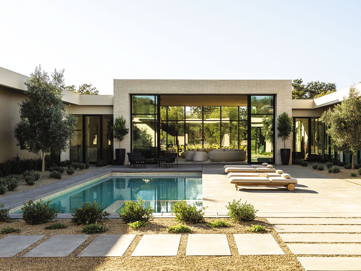 A sleek indoor pool surrounded by large windows in a modern home, showcasing contemporary design and natural light.