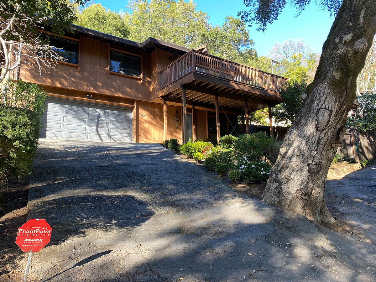 A residential house featuring a garage is adjacent to a bright red stop sign, signaling drivers to stop.