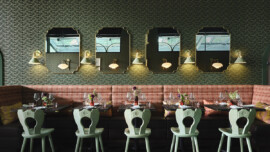 Elegant restaurant interior with patterned wallpaper, vintage mirrors, and wall sconces.