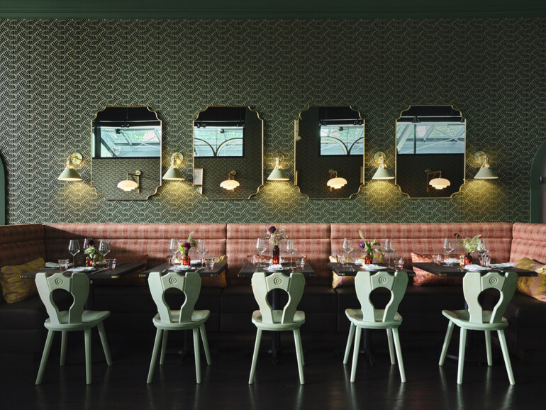 Elegant restaurant interior with patterned wallpaper, vintage mirrors, and wall sconces.