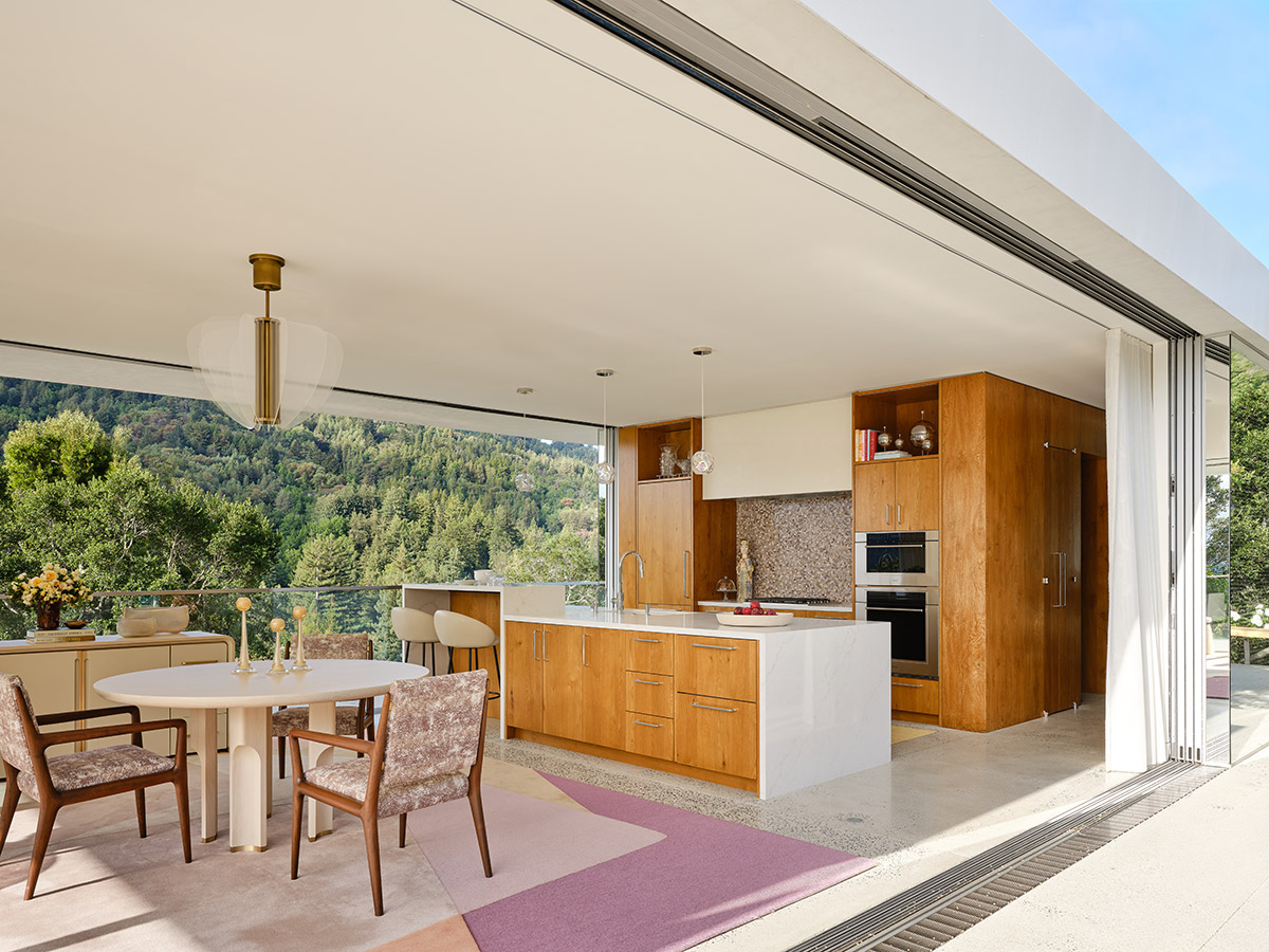 Modern open-concept kitchen with wooden cabinets, marble island, and round dining table