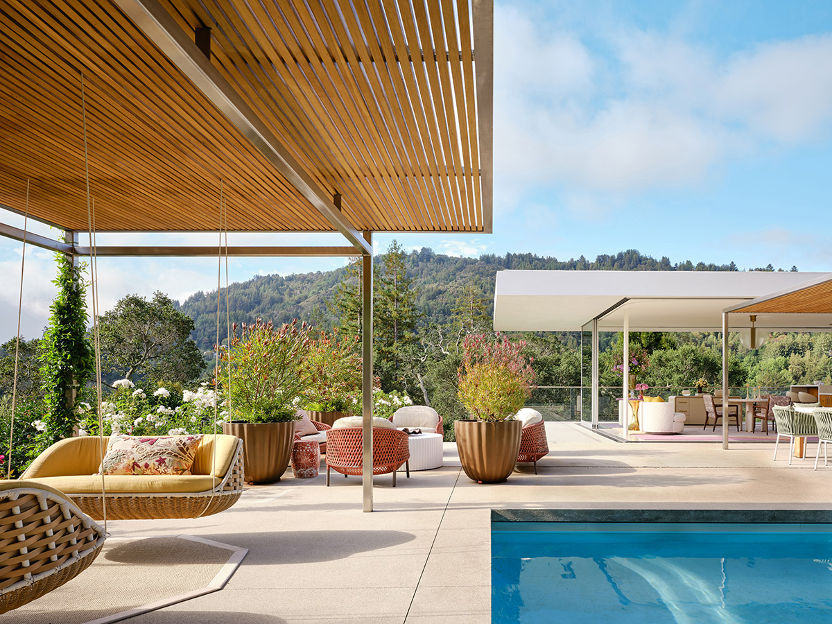 Spacious outdoor patio with stylish furniture, hanging chair, and pool. Overhead wooden slats provide shade.